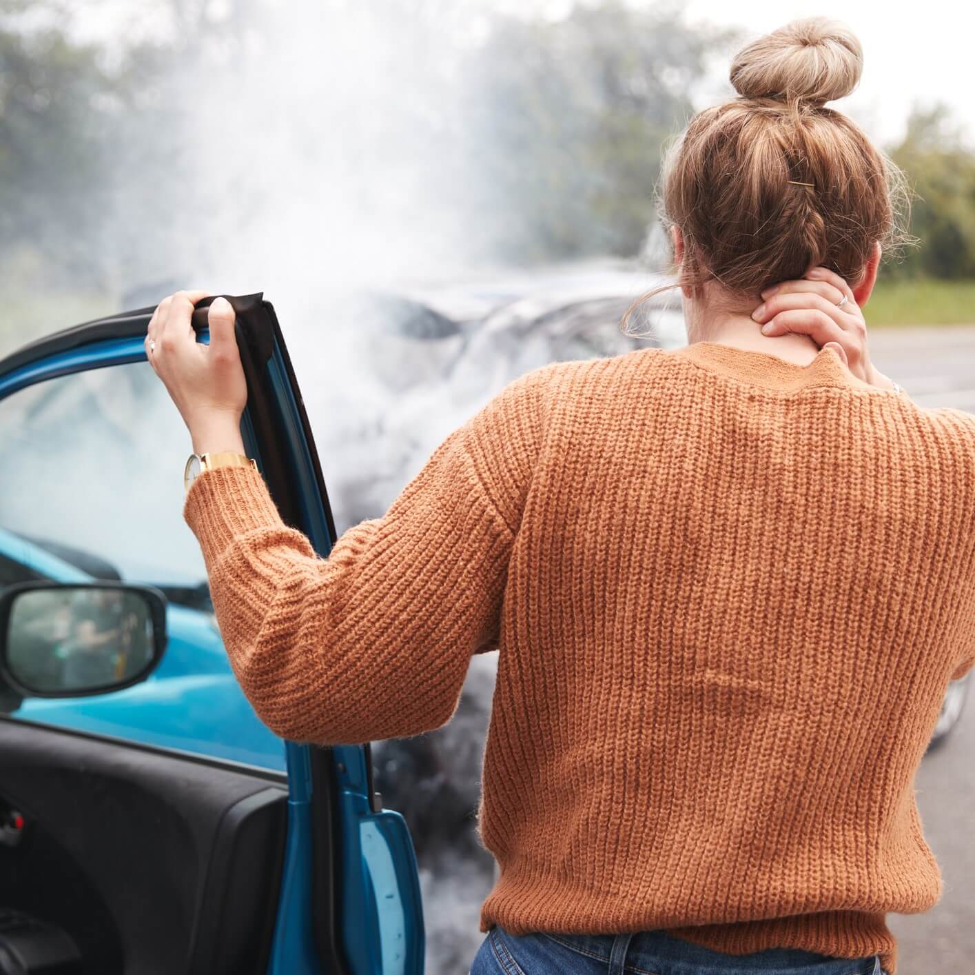 A woman gets out of her car and looks at a car accident