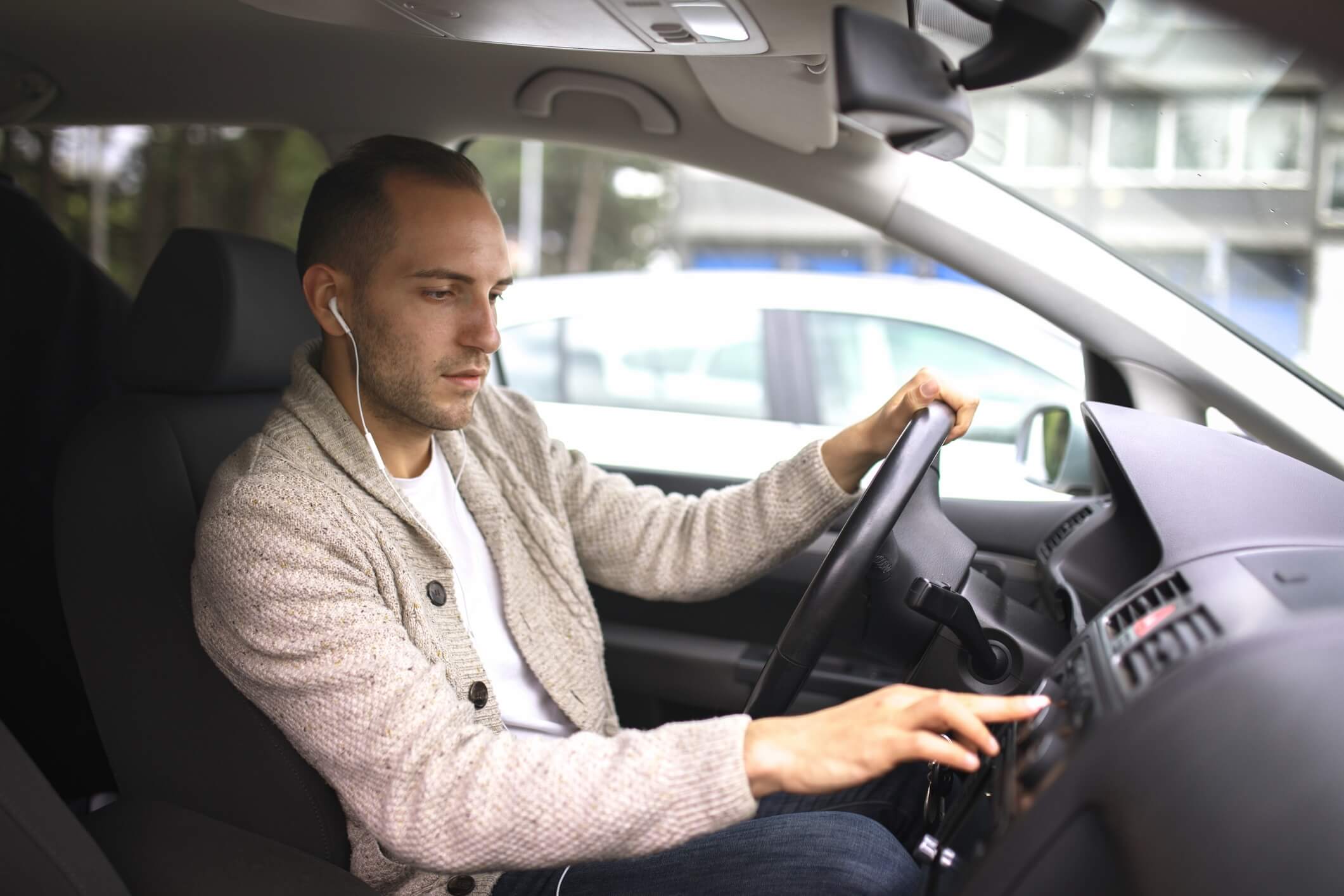 Man with earbuds in while driving.